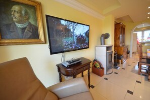 Ein Wohnzimmer mit Fernseher, Kamin, Essbereich und einem Bild an der Wand.