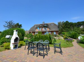 A house with a patio, outdoor seating, and a chimney. - 8a Reet-house part Sonnenkliff OG 3 bedrooms - Thatched-roof vacation apartments 8 Kröning (Gager)