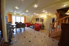 Amplia sala de estar con mesa de comedor, sofá rojo y escalera de madera.
