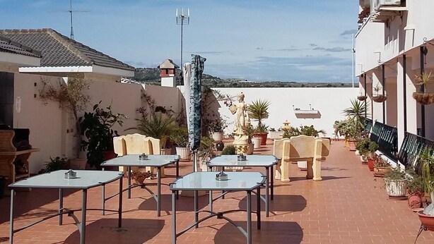 An outdoor patio with tables and chairs, a statue, and potted plants.