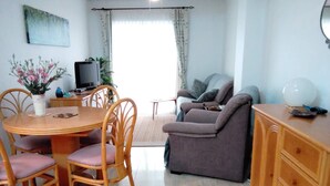 A living room with a dining table, chairs, a sofa, and a TV.