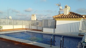 An indoor swimming pool with a tiled floor and a metal pool ladder.