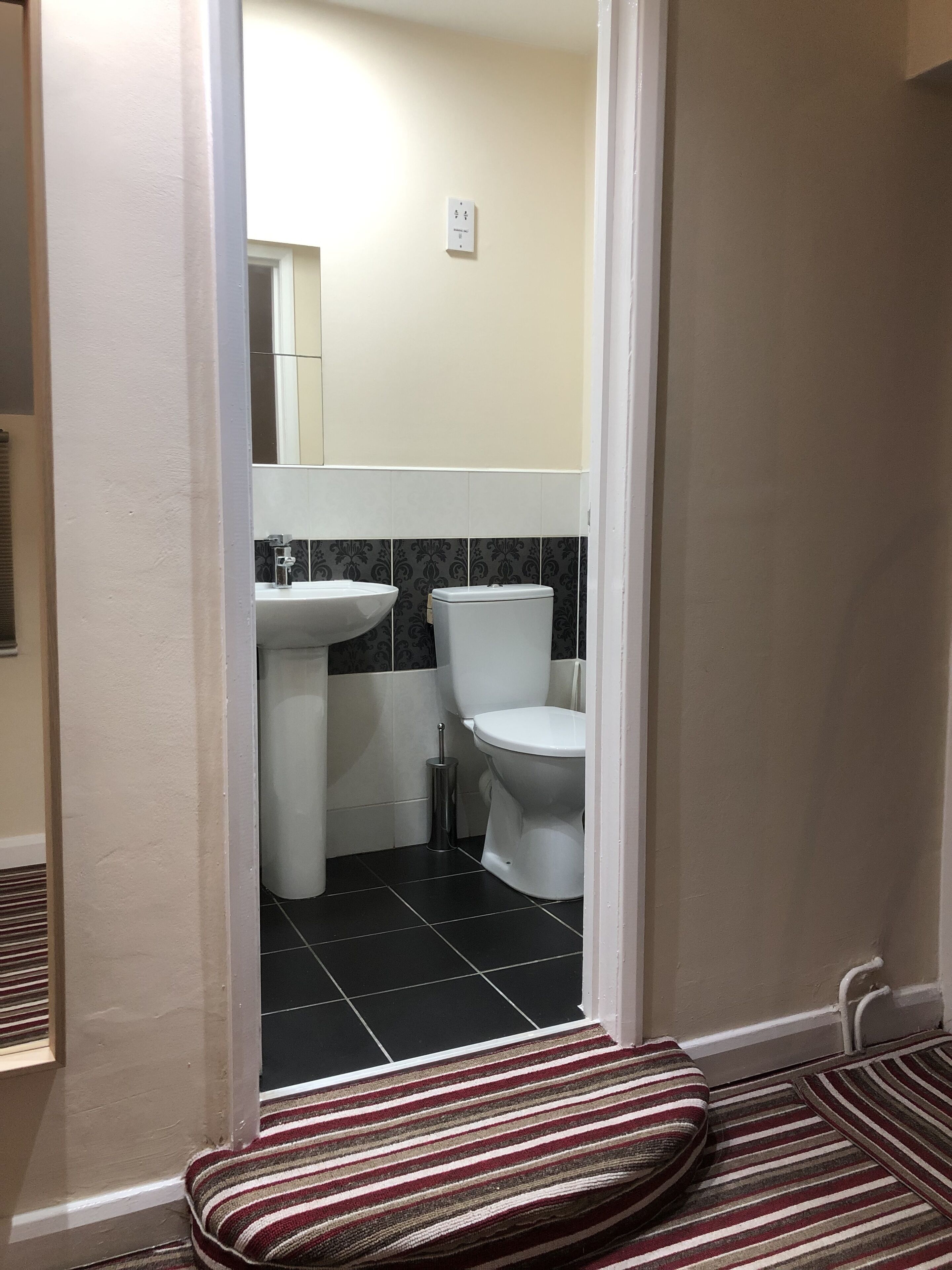 A bathroom with a toilet, sink, and tiled floor.