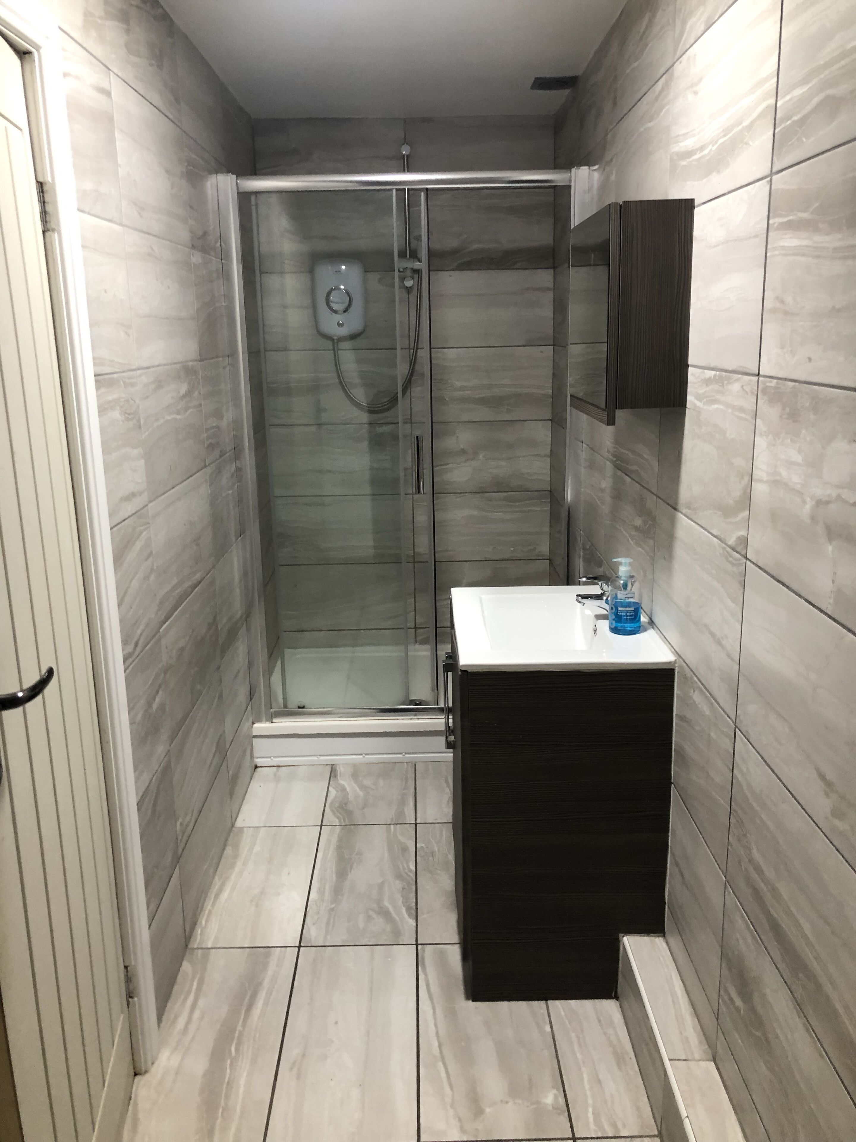 A modern bathroom with a glass-enclosed shower, a dark wooden vanity, and a white sink.