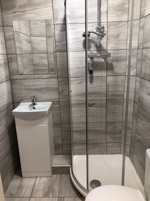 A bathroom with a shower, toilet, and sink. - Stifford clays farm hotel (Grays)