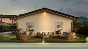 Een huis met een zwembad, buitenmeubels en decoratieve muurkunst.