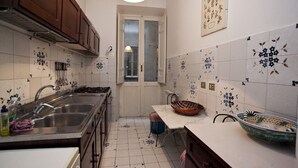 A kitchen with a sink, stove, cabinets, and decorative tiles.