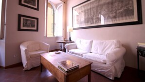A room with two white sofas, a wooden coffee table, and a large framed picture on the wall.