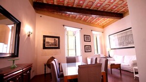 A dining area with a table and chairs, a sofa, and a ceiling with a patterned design.