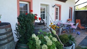 A patio area with outdoor seating, a small table, and potted plants. - An oasis for parents, a paradise for children (Tettnang)