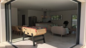 Ett modernt vardagsrum med ett fotbollsspel, en soffa och en matplats med stolar.