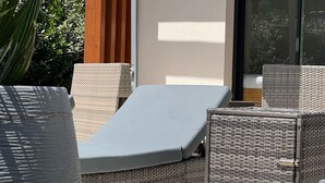 En utomhusplats med sittmöbler i rotting och ett stort parasoll.