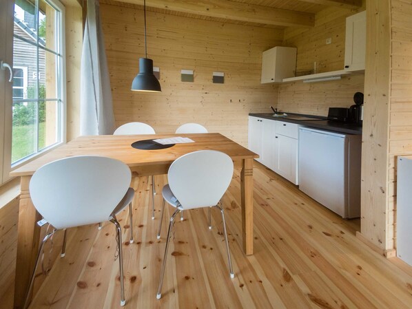 Een houten interieur met een eettafel, stoelen en een keukenhoek.