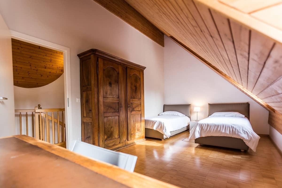 Un dormitorio con dos camas, un armario de madera y techo de madera.
