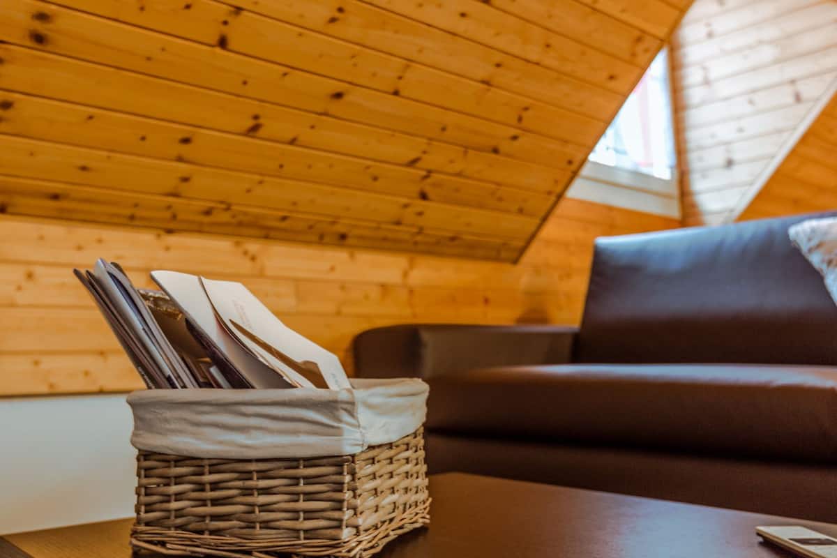Una habitación acogedora con techo de madera, un sofá marrón y una cesta de mimbre sobre una mesa.