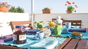 Una mesa de madera con mantel azul, un tarro de mermelada, una taza, una tetera, y varias tazas de té.