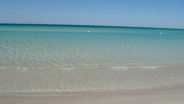 Una playa con agua turquesa cristalina y una orilla arenosa.