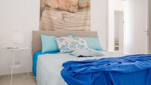 Un dormitorio con una cama, una mesita de noche y un tapiz en la pared.