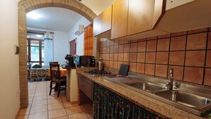 A kitchen with a granite countertop, stainless steel sink, and a tiled backsplash. - Studioflat 1 - Residenza Su Prelau Residence - Sardinia South West Coast (Gonnesa)