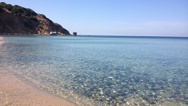 A clear beach with visible rocks and a distant building on a cliff. - Studioflat 1 - Residenza Su Prelau Residence - Sardinia South West Coast (Gonnesa)