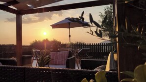 A patio area with wicker furniture, an umbrella, and a view of the sunset. - Studioflat 1 - Residenza Su Prelau Residence - Sardinia South West Coast (Gonnesa)