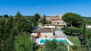 A villa with a swimming pool, stone buildings, and lush greenery.
