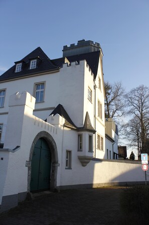 A white building with a green door, a small archway, and a tiled entrance.