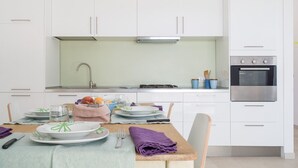 A modern kitchen with white cabinets, a stainless steel stove, and a built-in oven. - Salento Villa Emma - Green Apartment with Garden (Porto Cesareo)