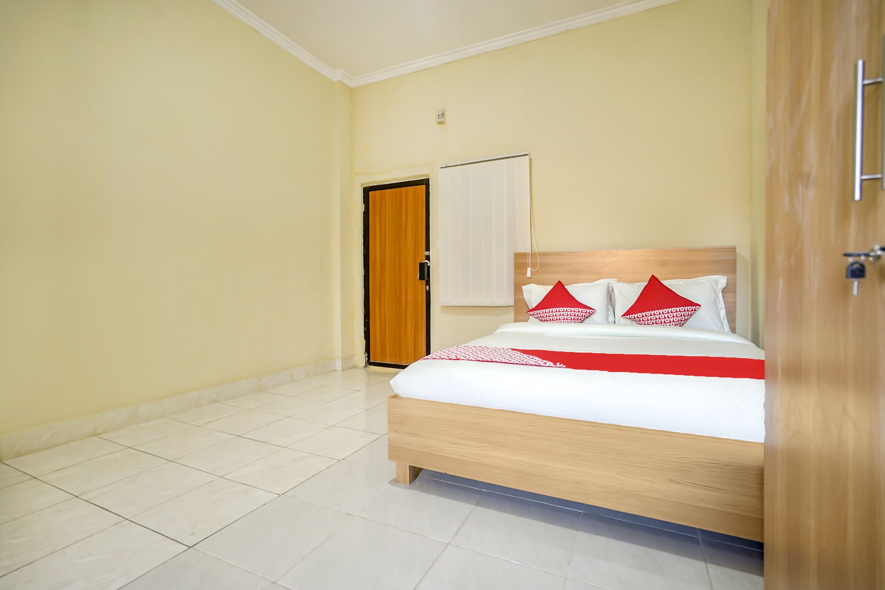 Ein Schlafzimmer mit einem Bett, einer Holztür und einer weißen Wand.