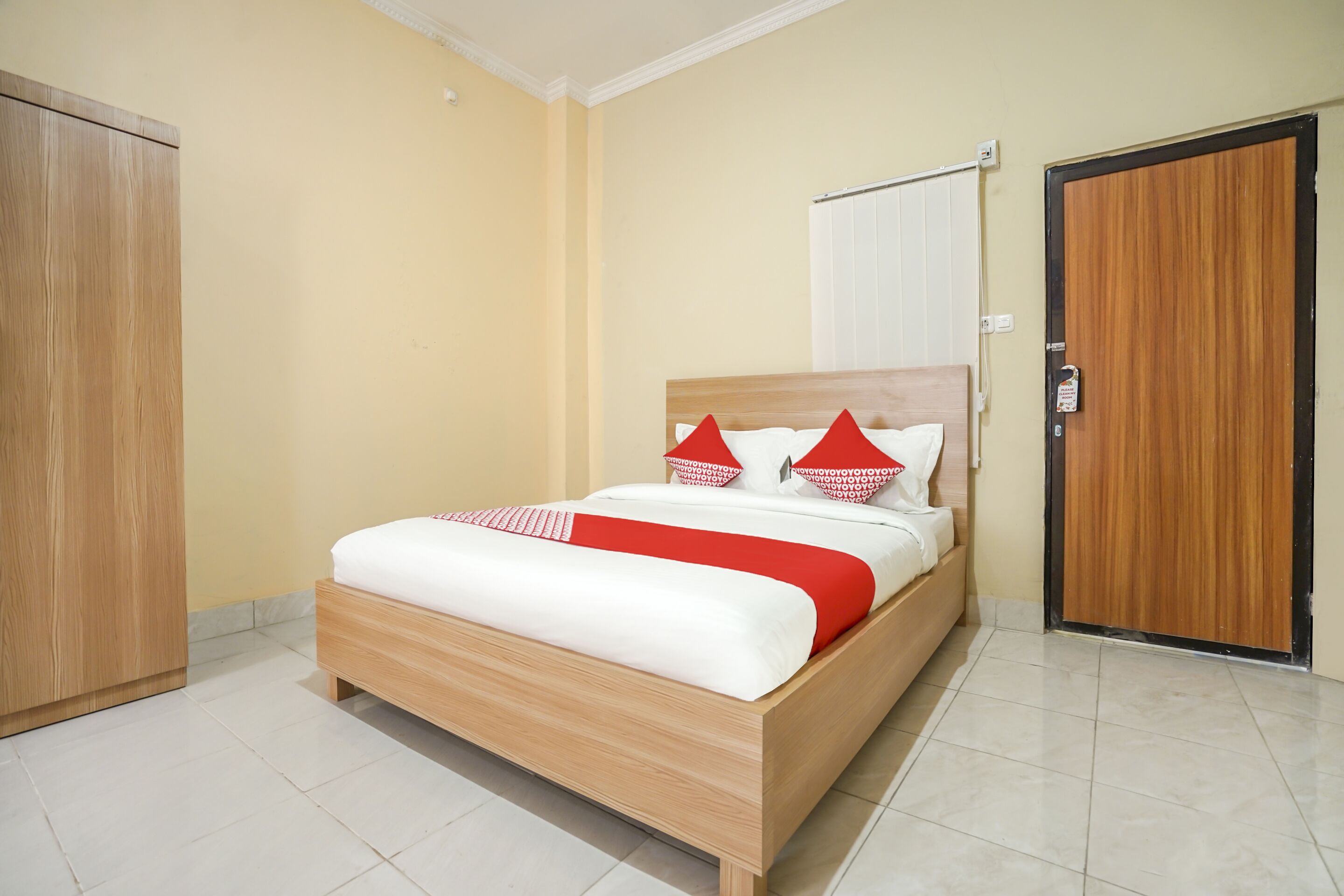 A neatly arranged bedroom with a wooden bed, a wardrobe, and a door.