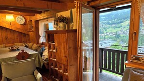 Interior de fusta acollidor amb zona de menjador, un armari de fusta i un balcó amb vistes panoràmiques.