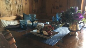 Taula de menjador de fusta servida amb vidrieria blava, un arranjament floral al centre i un pot petit de melmelada.