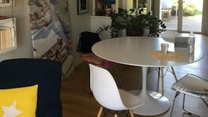 Un'area pranzo moderna con un tavolo rotondo, sedie bianche e un lampadario.