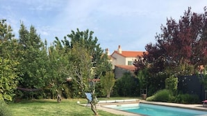 Un giardino sul retro con piscina, un pontile in legno e un tavolo con sedie.