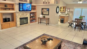 A spacious living room with a fireplace, a television, and a dining area with a table and chairs.