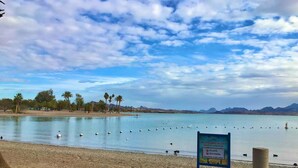 A beach with a sign prohibiting lifeguards on duty and no glass or alcohol in park areas.