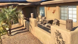 A house with a patio area, solar panels, and a palm tree.