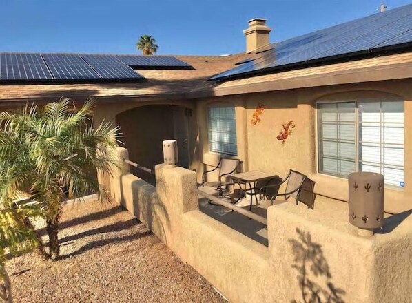 Ein Haus mit Terrasse, Solaranlage und einer Palme.