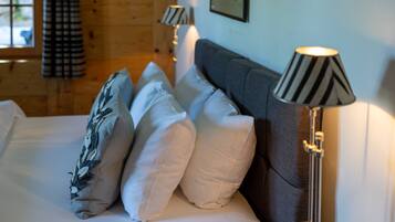 A bed with white linens, a grey headboard, and two lamps with striped lampshades.