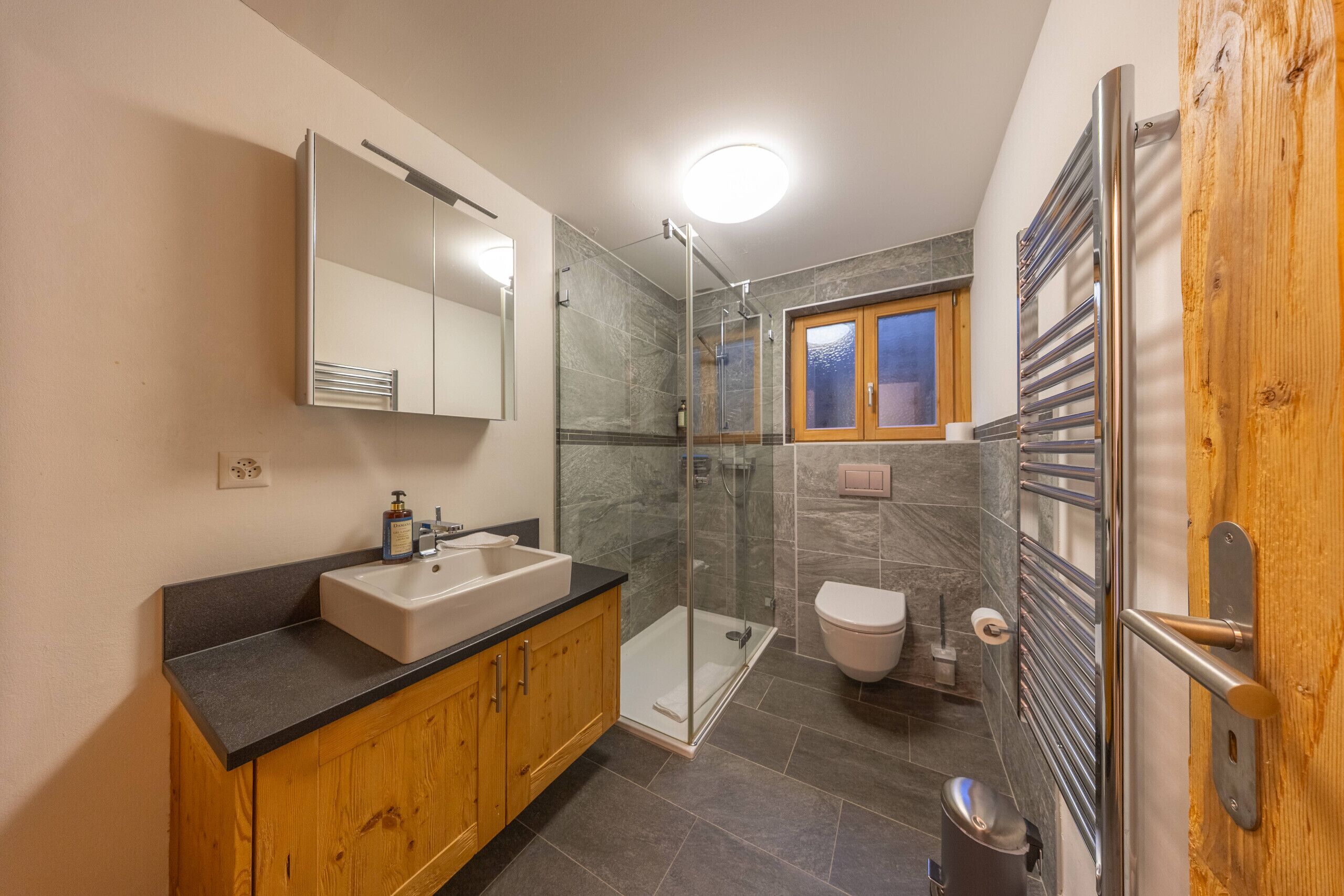 A bathroom with a sink, mirror, shower, toilet, and towel rack.