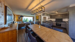 A modern kitchen with a wooden dining table, built-in appliances, and a pendant light. - Chalet Riquet - ski-in/out - luxe (Haute-Nendaz)