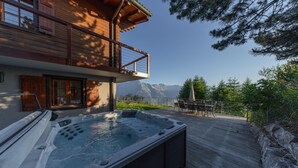 A wooden deck with a hot tub, a dining area, and a mountain view. - Chalet Riquet - ski-in/out - luxe (Haute-Nendaz)