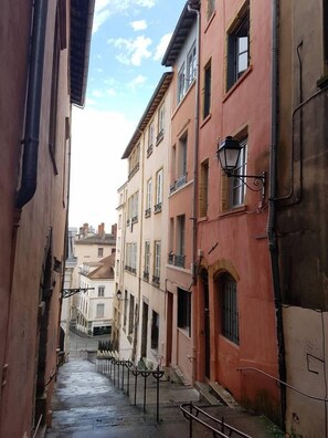 A narrow street with buildings on either side, featuring balconies and a street lamp. - Studio - 2P - Vieux Lyon (Lyon)