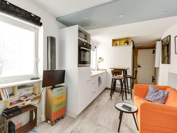 A compact living space with a kitchenette, a television, a sofa, and a small dining area. - Studio - 2P - Vieux Lyon (Lyon)