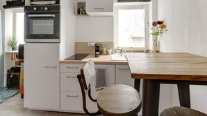 A modern kitchen with a built-in oven, microwave, and sink. There is a wooden dining table and a chair. - Studio - 2P - Vieux Lyon (Lyon)