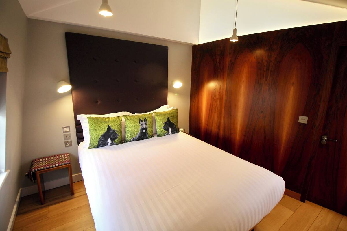 A bedroom with a large bed, a wooden headboard, and a wooden wardrobe.