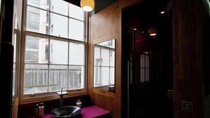 Une salle de bain moderne avec une grande fenêtre, un meuble-lavabo en bois, un évier et un miroir.