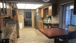 Une cuisine dotée de meubles en bois, d’un plan de travail en granit, d’un réfrigérateur et d’un coin repas avec une table et des chaises.