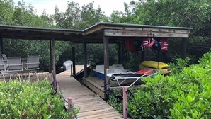 Un espace extérieur abrité, doté d’une terrasse en bois qui mène à un coin salon avec des chaises et une table.