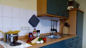Una cocina con estufa, ollas, tabla de cortar y varios ingredientes.